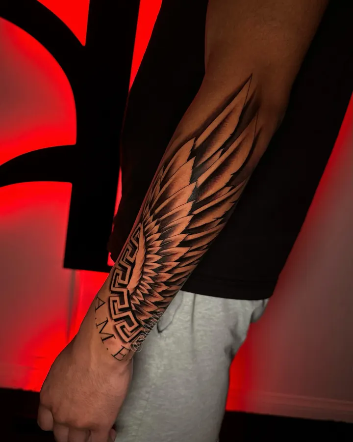 Black and grey tattoo by Dre: winged pattern, forearm