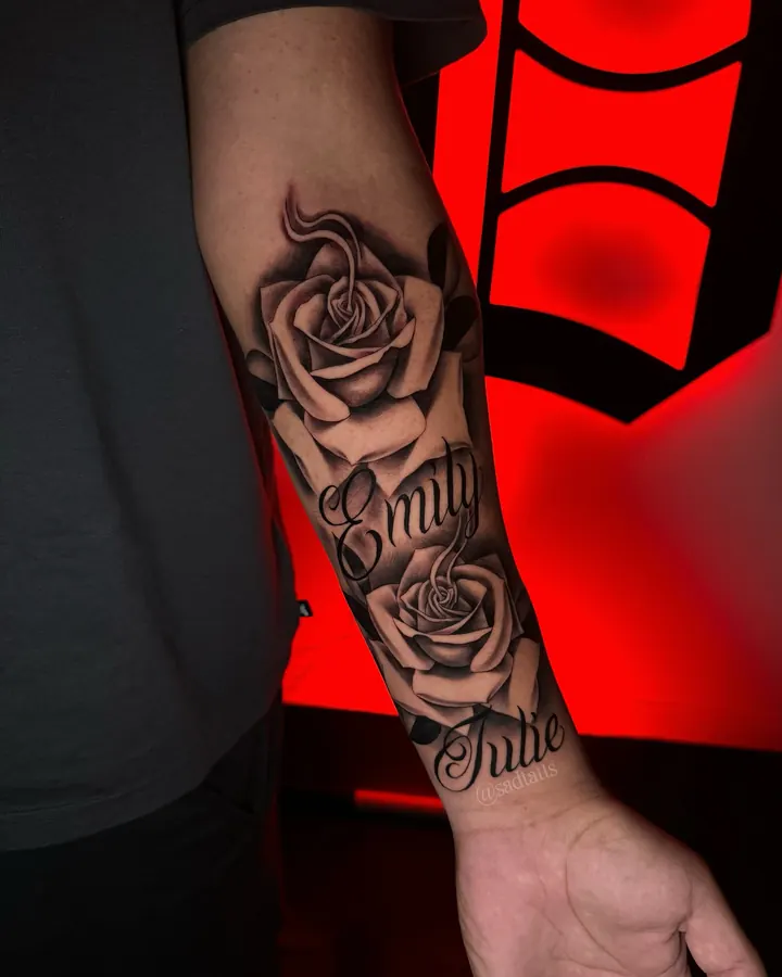 Black and grey tattoo by Dre: roses with script, forearm