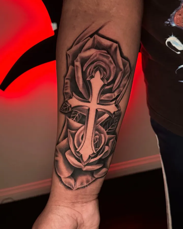 Black and grey tattoo by Dre: rose and cross, forearm