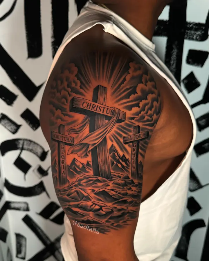 Black and grey tattoo by Dre: cross and clouds, shoulder