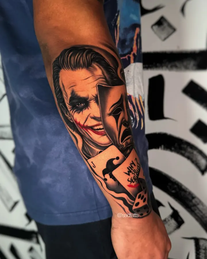 Black and grey tattoo by Dre: joker mask and dice, forearm