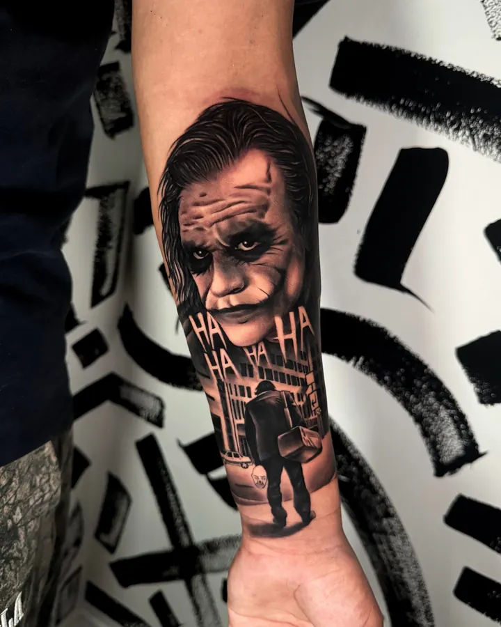 Black and grey tattoo by Dre: Joker with HA HA, forearm
